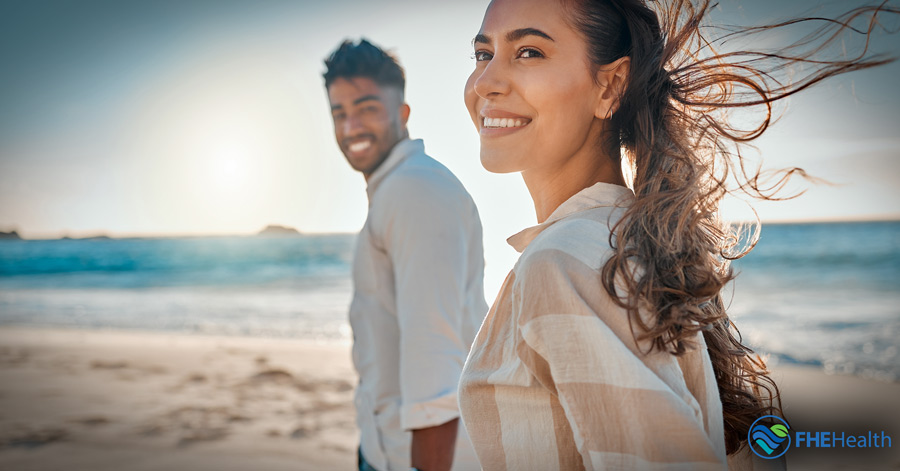 A couple standing on a beach that has built intimacy in their relationship and have improved mental health
